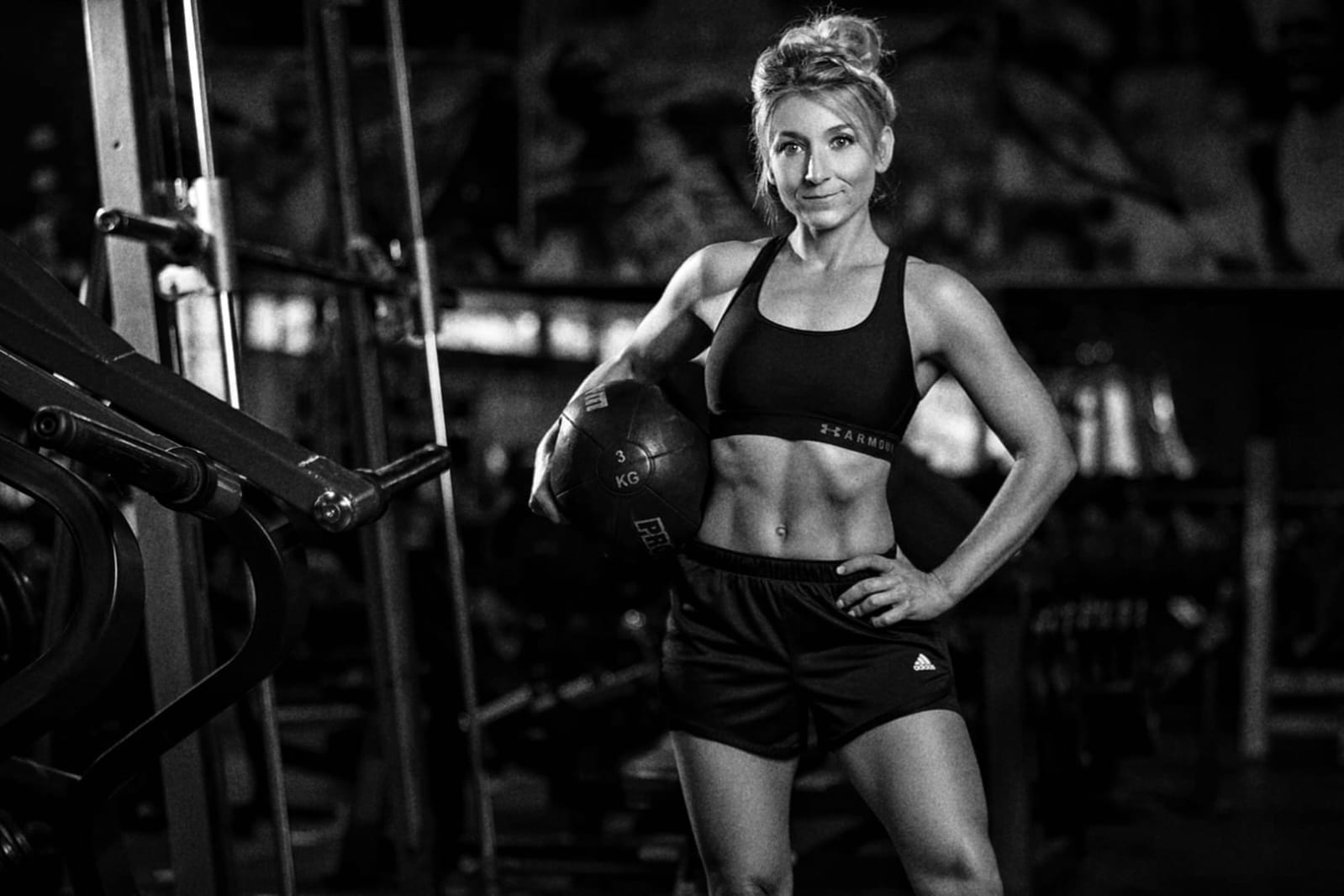 Alice holding a medicine ball in a gym, looking at the camera